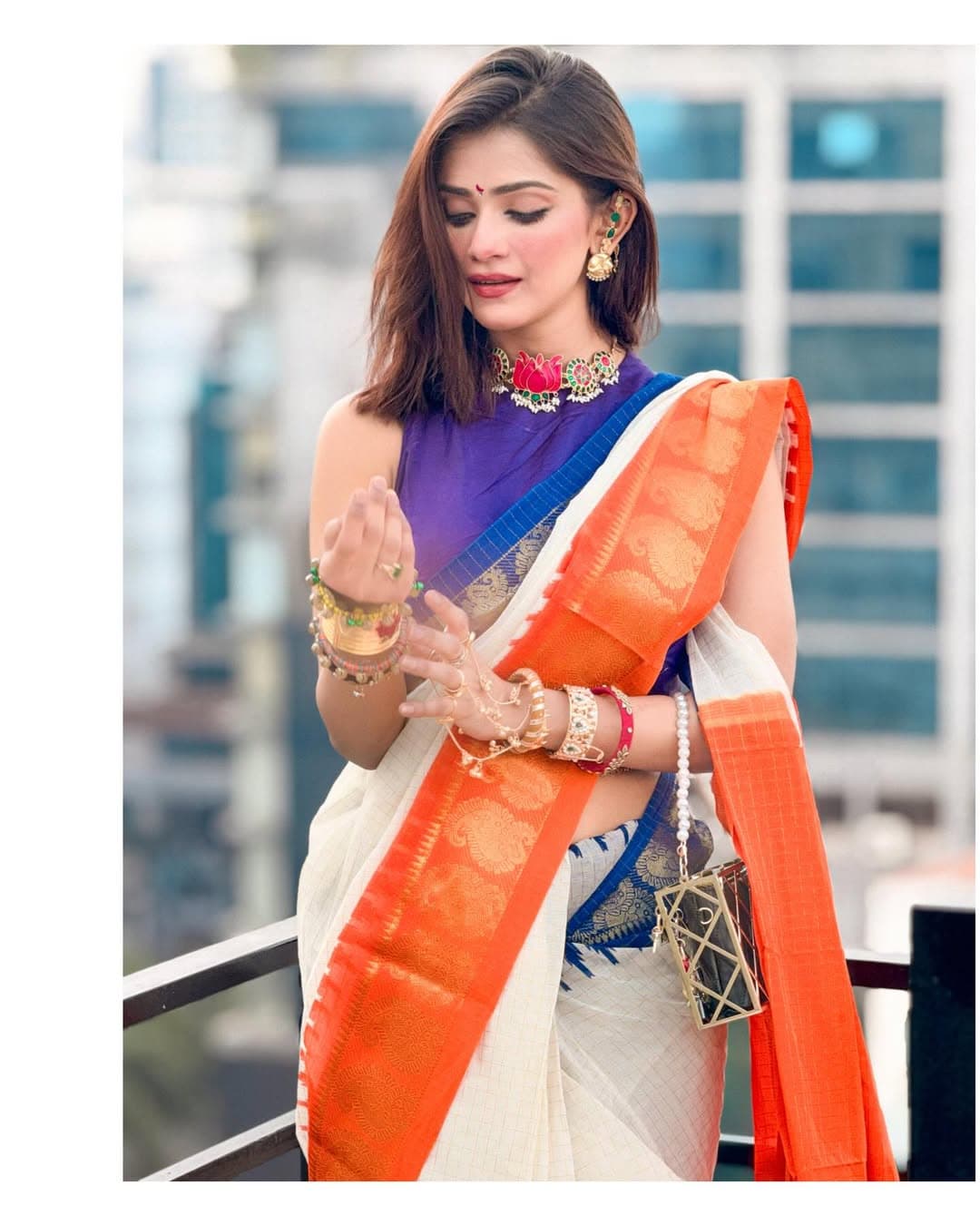 তিশার পরনে সাদা তাঁতের শাড়ি, তাতে উজ্জ্বল কমলা ও নেভি ব্লু গঙ্গা-যমুনা জরীপাড়।